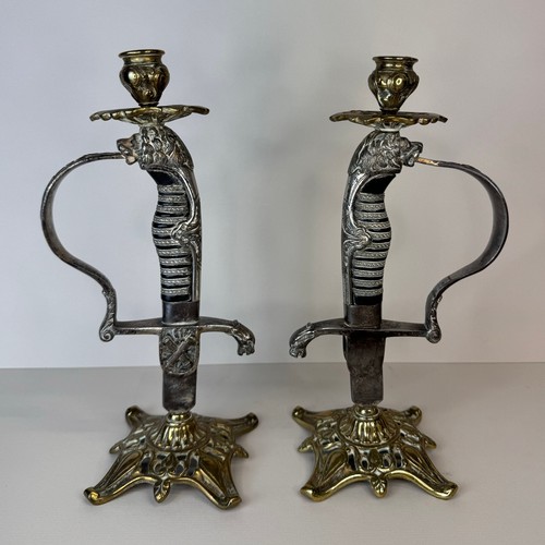 119 - A pair of brass mounted military sword handle candlesticks, 27cms h