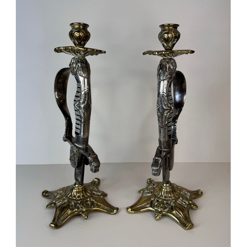 119 - A pair of brass mounted military sword handle candlesticks, 27cms h