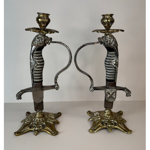 119 - A pair of brass mounted military sword handle candlesticks, 27cms h