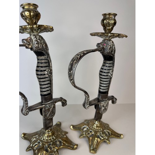 119 - A pair of brass mounted military sword handle candlesticks, 27cms h