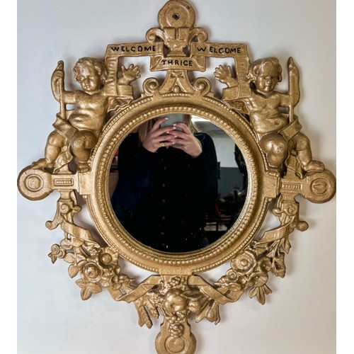 121 - A Victorian gilt metal framed mirror, cast with cherubs and inscribed; Welcome, Welcome, Thrice