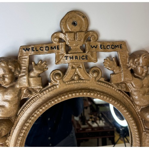 121 - A Victorian gilt metal framed mirror, cast with cherubs and inscribed; Welcome, Welcome, Thrice