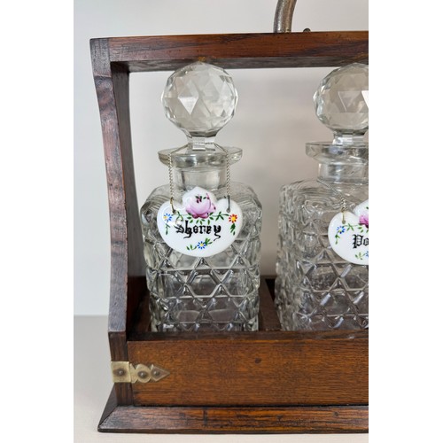 123 - An early 20th Century oak tantalus, with three glass decanters and porcelain spirit labels