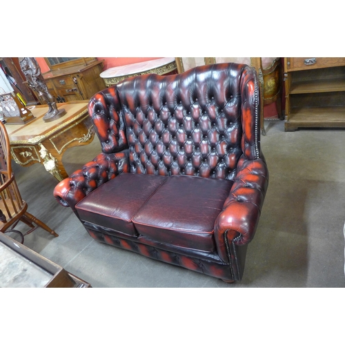 155 - An oxblood red leather Chesterfield wingback sofa