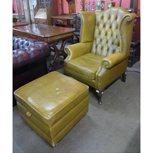 152 - A mahogany and tan leather Chesterfield wingback armchair and pouffe