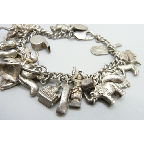 1068 - A silver charm bracelet, with approximately 26 silver and white metal charms, 94.1g