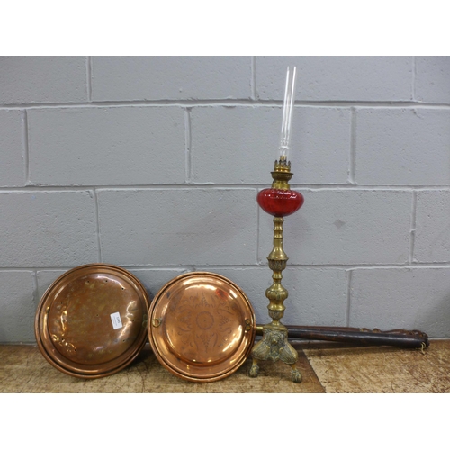 1145 - A brass oil lamp with cranberry glass reservoir and two copper and wooden handled bed warmers **PLEA... 