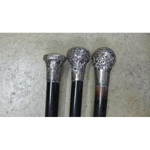 806 - Three silver topped ebonised walking canes with engraved decoration to the tops