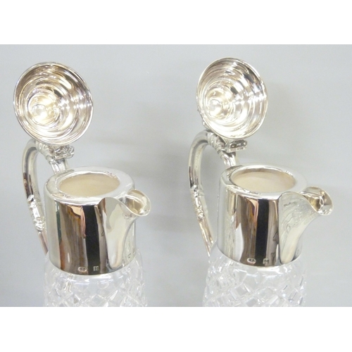 857 - A pair of silver topped glass claret jugs, Birmingham 1989