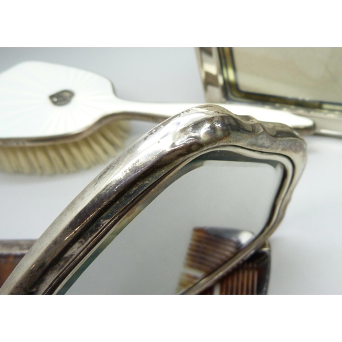 894 - A silver photograph frame, a silver and enamelled hand mirror and brush and a silver mounted comb