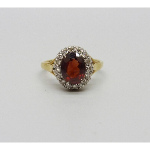 980 - An 18ct gold garnet and diamond halo ring, 4.4g, L