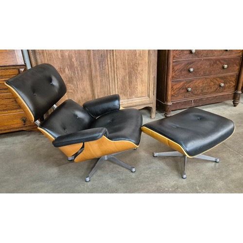 14 - A Charles & Ray Eames style simulated walnut and black leather revolving lounge chair and ottoman