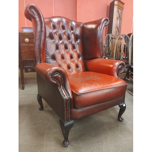 128 - An oxblood red leather Chesterfield wingback armchair