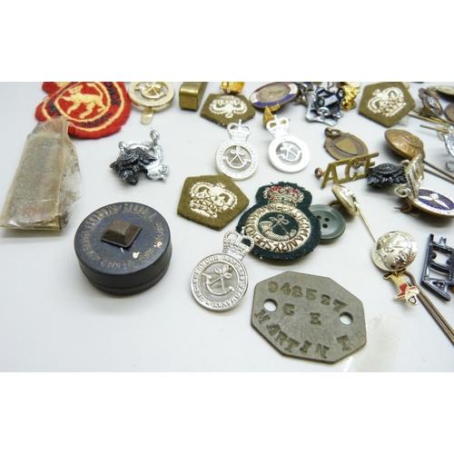 869 - A collection of military badges, dog tags, other badges, etc.