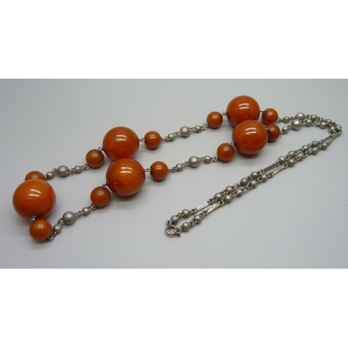 1003 - A large amber coloured bead necklace mounted on a white metal chain