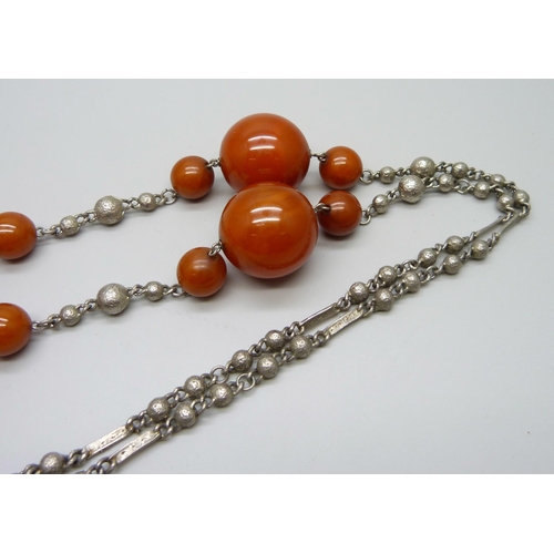 1003 - A large amber coloured bead necklace mounted on a white metal chain