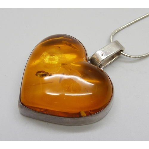 1005 - A silver mounted amber pendant on chain, 40mm wide