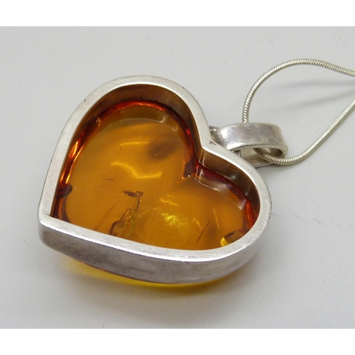 1005 - A silver mounted amber pendant on chain, 40mm wide