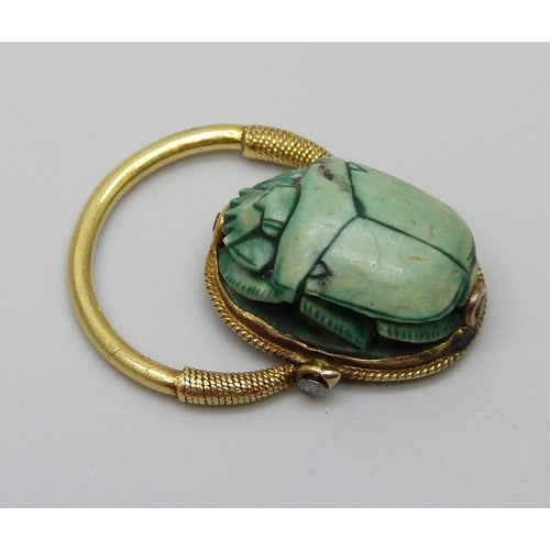 921 - An Egyptian yellow metal set scarab beetle ring with carved scene verso, 5.1g, size K