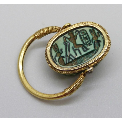 921 - An Egyptian yellow metal set scarab beetle ring with carved scene verso, 5.1g, size K