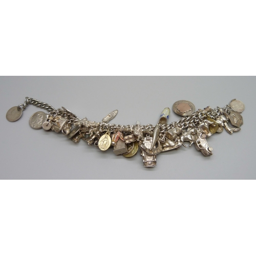 922 - A heavy charm bracelet with silver and white metal charms and coins, total weight 164g