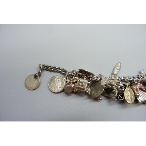 922 - A heavy charm bracelet with silver and white metal charms and coins, total weight 164g