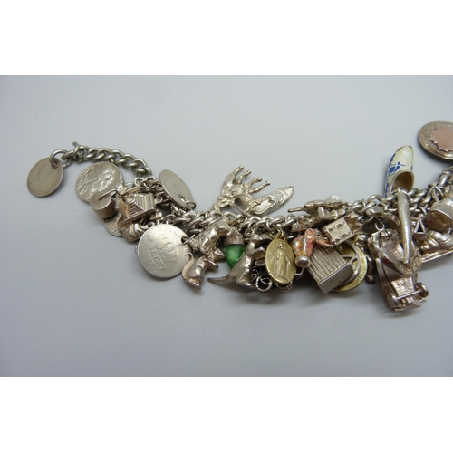 922 - A heavy charm bracelet with silver and white metal charms and coins, total weight 164g