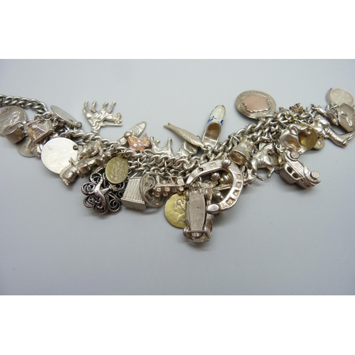 922 - A heavy charm bracelet with silver and white metal charms and coins, total weight 164g