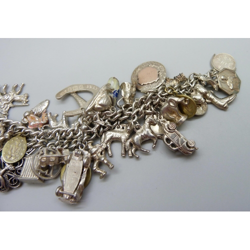 922 - A heavy charm bracelet with silver and white metal charms and coins, total weight 164g