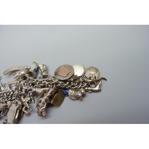 922 - A heavy charm bracelet with silver and white metal charms and coins, total weight 164g