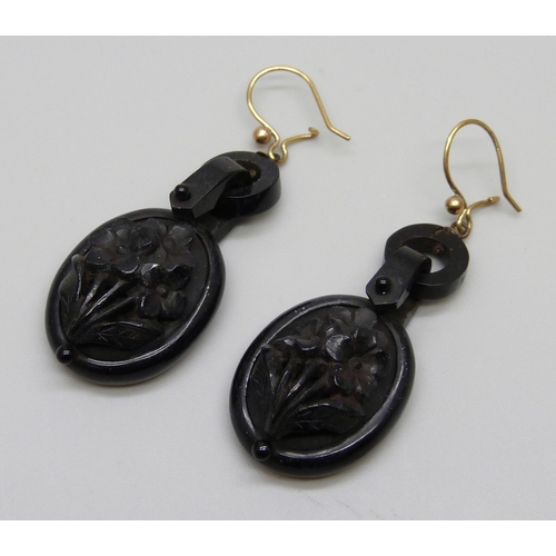 928 - A pair of carved jet earrings depicting flowers, on yellow metal hooks