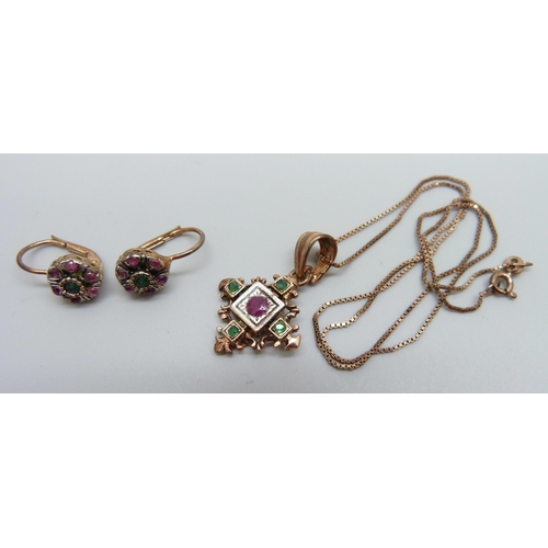 945 - A silver gilt ruby and emerald set pendant on a chain and a pair of matching earrings