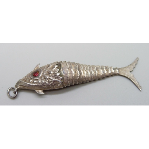 953 - A white metal articulated fish pendant with red paste set eyes, continental control marks, 75mm