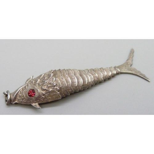 953 - A white metal articulated fish pendant with red paste set eyes, continental control marks, 75mm