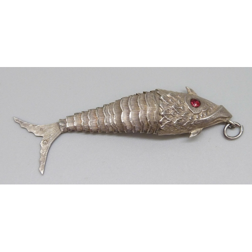 953 - A white metal articulated fish pendant with red paste set eyes, continental control marks, 75mm