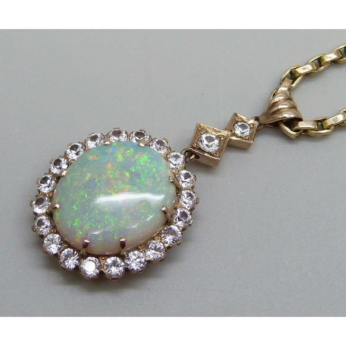 980 - A yellow metal cluster drop pendant set with a central opal and white stone border, on a 9ct gold ch... 