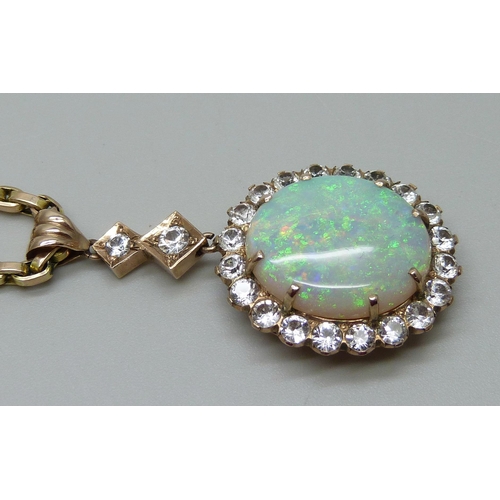 980 - A yellow metal cluster drop pendant set with a central opal and white stone border, on a 9ct gold ch... 