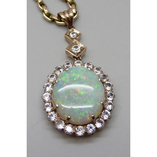 980 - A yellow metal cluster drop pendant set with a central opal and white stone border, on a 9ct gold ch... 