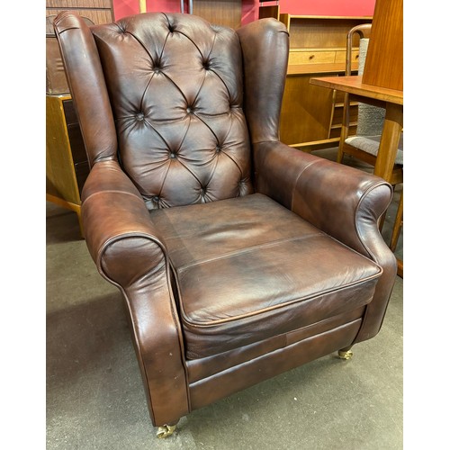 107 - A chestnut brown leather Chesterfield wingback armchair