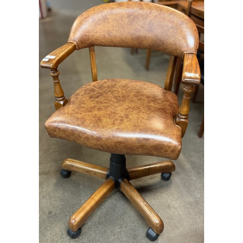 146 - An elm and brown leather upholstered revolving desk chair