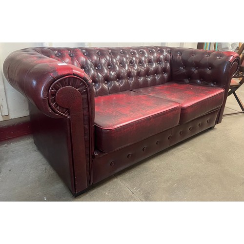 102 - An oxblood faux red leather Chesterfield sofa