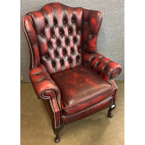 83 - An oxblood red leather Chesterfield wingback armchair