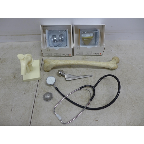 2069 - An anatomical model of a knee, a stethoscope, a model bone, knee replacement parts, etc.