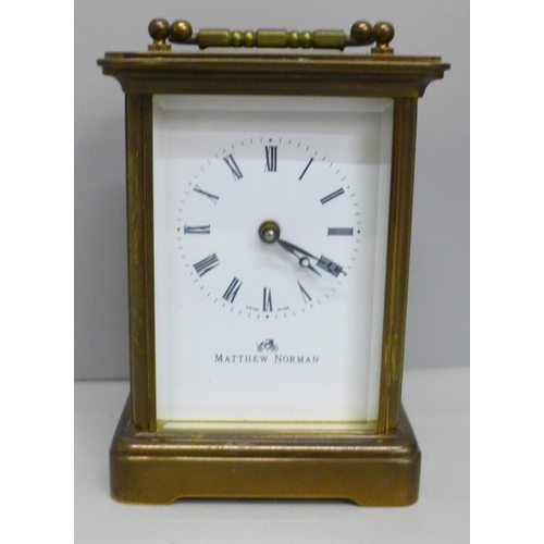 613 - A Matthew Norman brass and four glass sided clock, with key