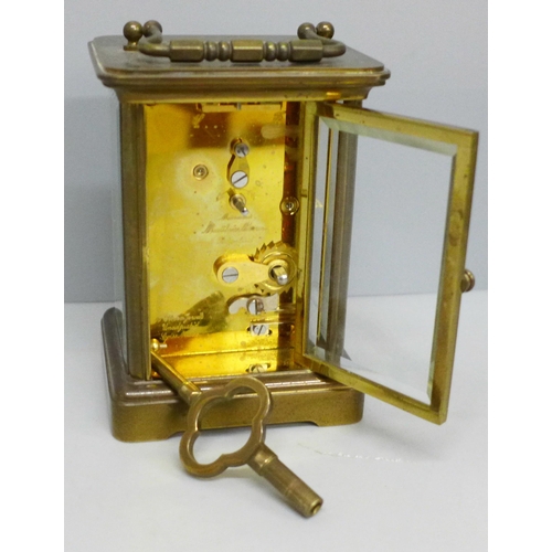 613 - A Matthew Norman brass and four glass sided clock, with key