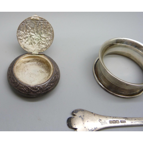 843 - A silver plated snuff box, an embossed white metal pill box, a silver spoon and a silver napkin ring... 