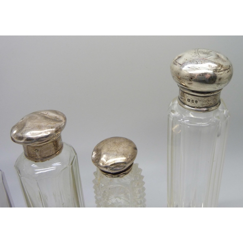 888 - Four glass scent bottles with silver tops, tops a/f, dented