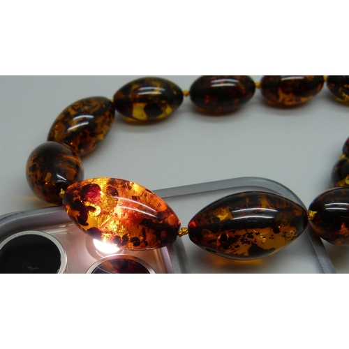 957 - A string of Baltic amber beads, silver mounted