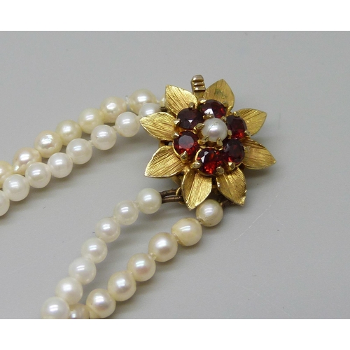 973 - A graduated double row pearl necklace with 9ct gold, garnet and pearl clasp, 50cm, (different colour... 