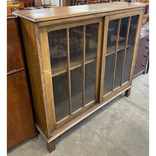 130 - An early 20th Century oak sliding door bookcase